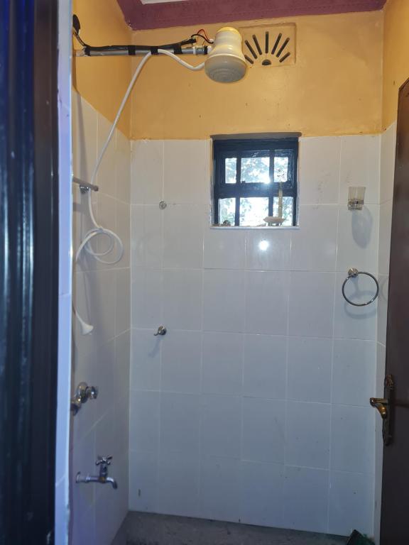 a bathroom with a white shower with a window at Christa's Haven in Siaya