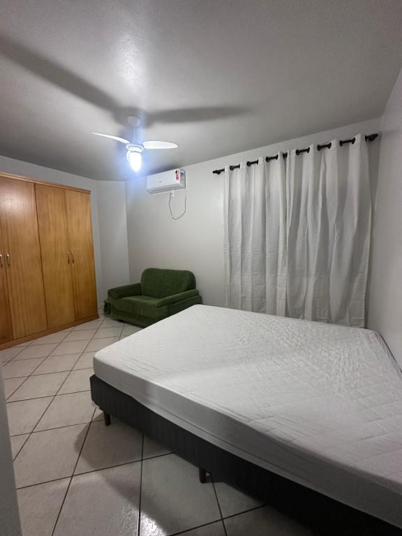 ein Schlafzimmer mit einem Bett und einem grünen Stuhl in der Unterkunft Apartamento amplo em meia praia - poucos metros do mar in Itapema
