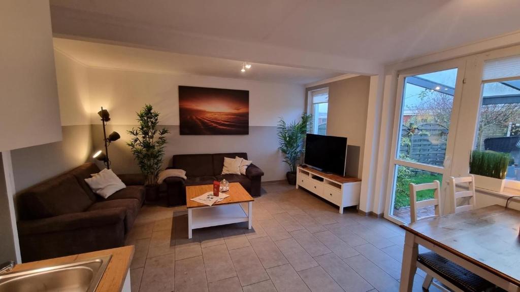 sala de estar con sofá y TV en Ferienhaus-Klippenbarsch, en Dornumersiel