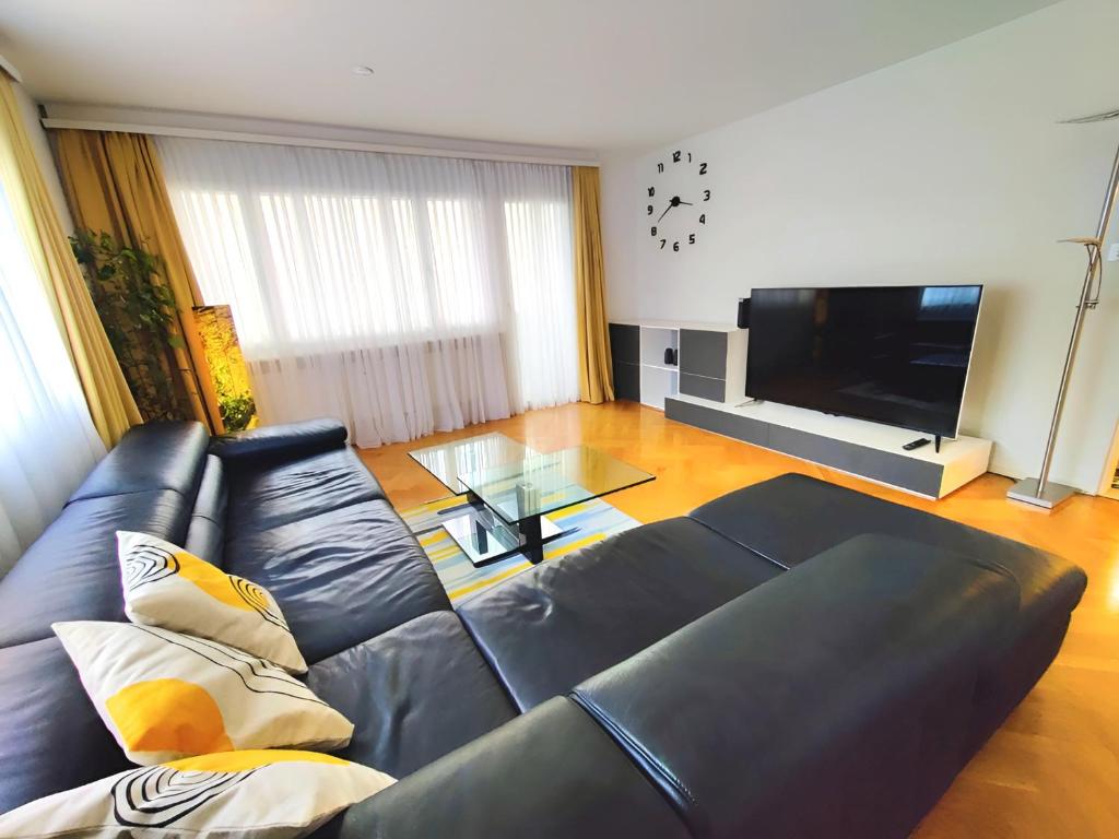 ein Wohnzimmer mit einem schwarzen Ledersofa und einem Flachbild-TV in der Unterkunft Top apartment with 2 bedrooms and fully equiped in Haag