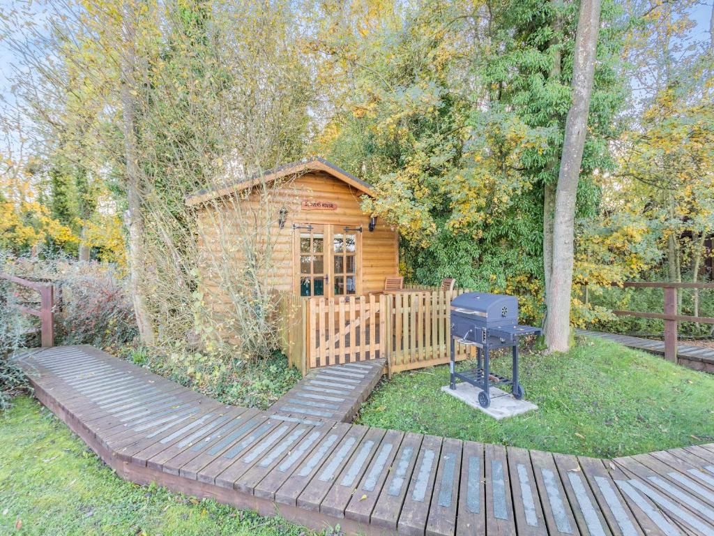 uma cabana de madeira com uma grelha no quintal em Beavers- Uk45706 em Cambridge