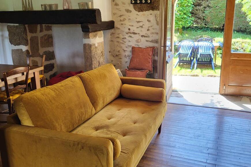 un sofá marrón en una sala de estar con patio en Gites les Tillets -Noyer, en Montet-et-Bouxal