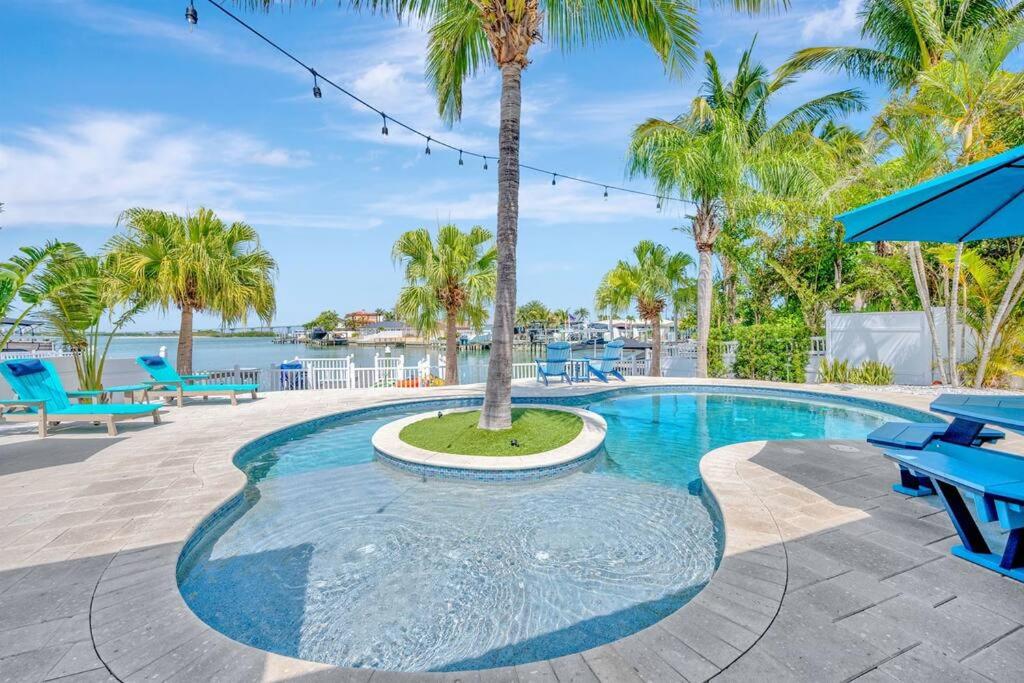 a pool with blue benches and a palm tree at Island Paradise 3 Bed Waterfront/Heated Pool in Clearwater Beach