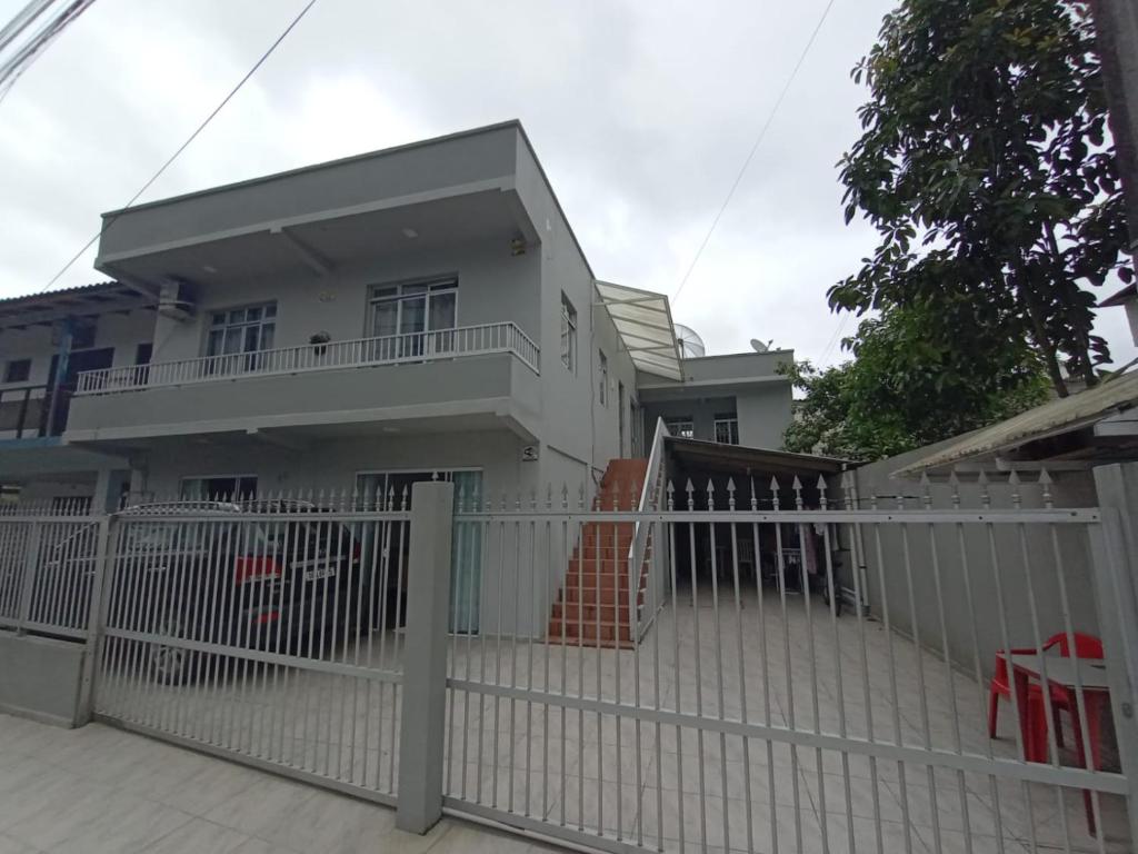 a white fence in front of a white house at Pequeno, más aconchegante in Itapema