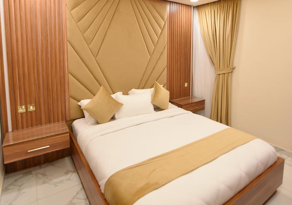 a bedroom with a bed with white sheets and pillows at الدانة للشقق الفندقية in Kuwait