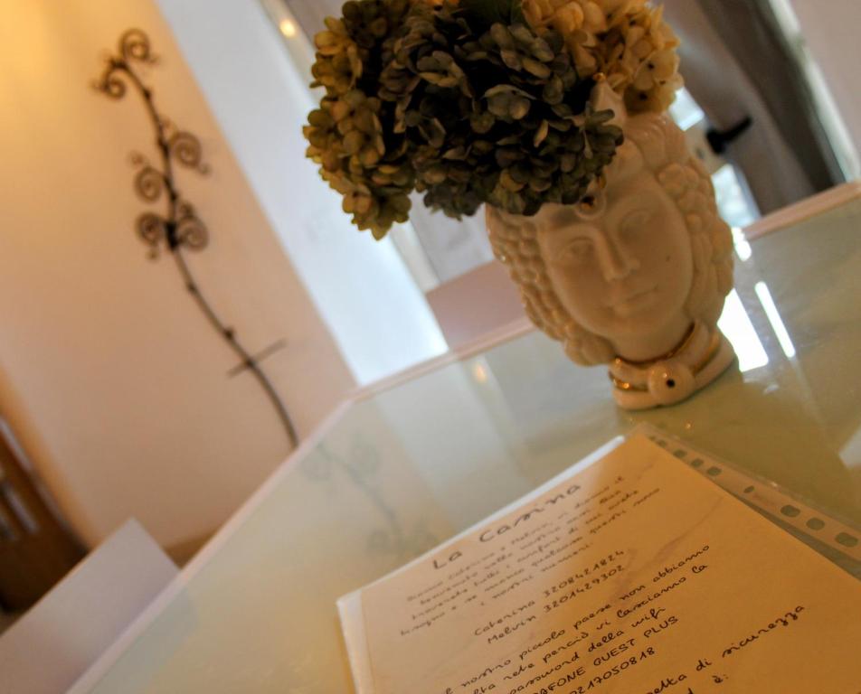 a vase with flowers on a glass table with a paper at La Casina in Montecatini Val di Cecina