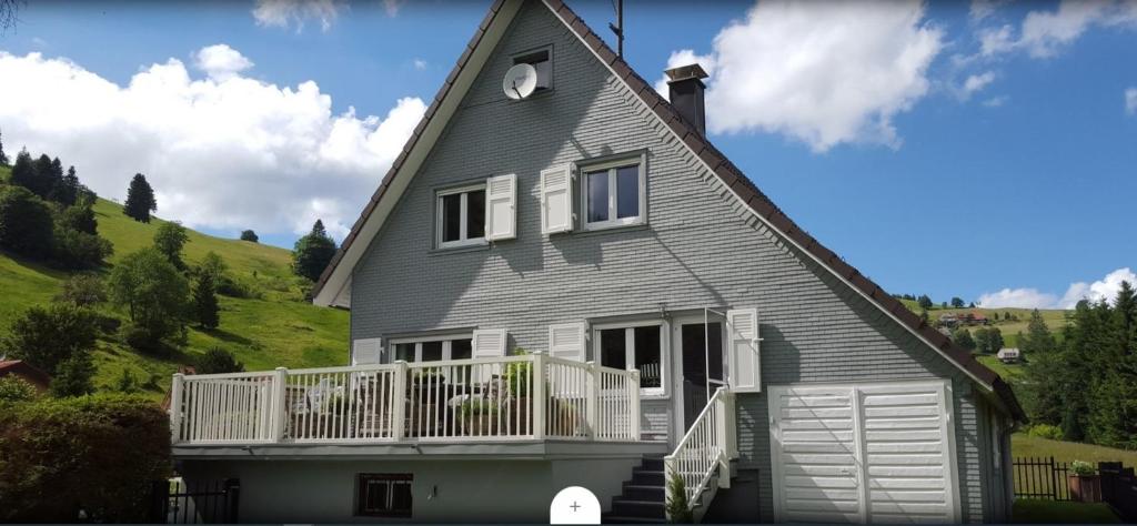 a gray house with a white balcony on a hill at La Faya "Molerhüsli"- Gemütliches, gehobenes Ferienhaus in Muggenbrunn -Feldberg in Muggenbrunn