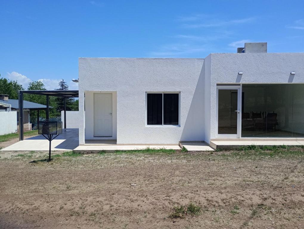 Casa blanca con puerta y ventanas blancas en Casa Villa Rumipal en Villa Rumipal