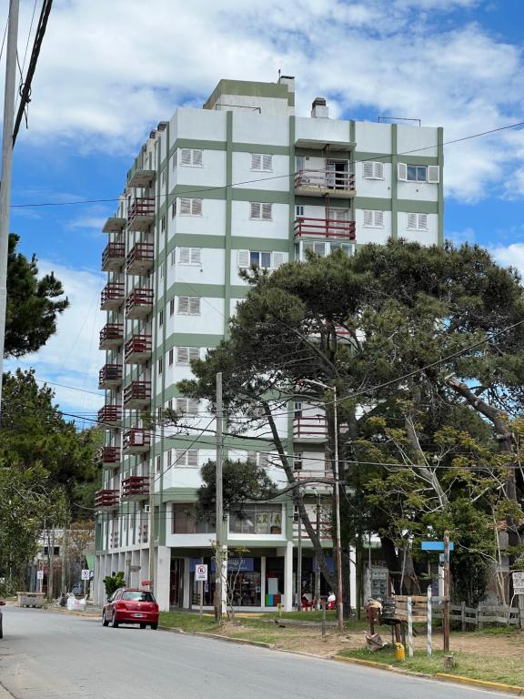 um edifício branco alto com uma árvore em frente em Sexto al mar em Santa Teresita