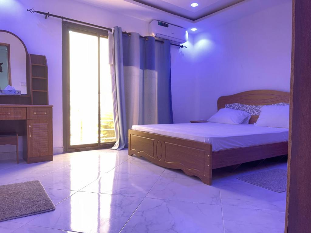 1 dormitorio con cama y ventana grande en Résidence Cheikh Mahy Cisse Appartements, studios et chambres a louer meublé et climatisé, en Kaolack