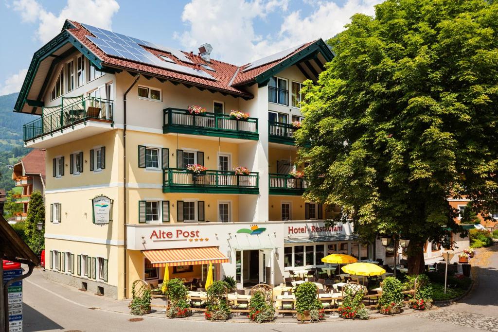 un grande edificio con tavoli e ombrelloni di fronte di Hotel Alte Post a Feld am See
