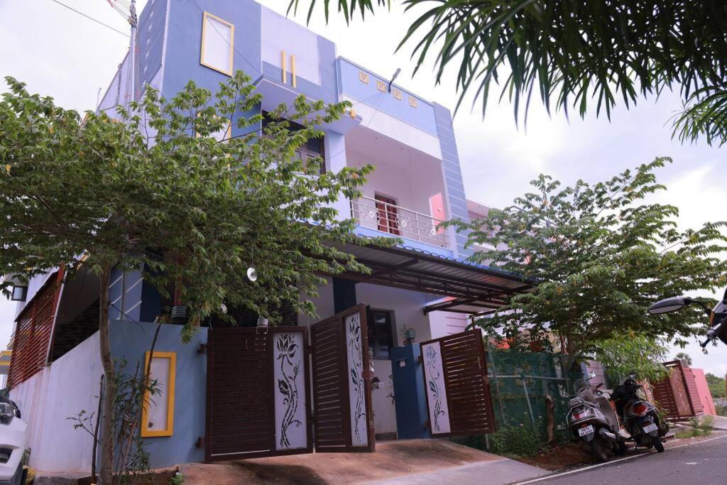 a blue and white building with a motorcycle parked in front at SUCYL's Homestay in Tirunelveli