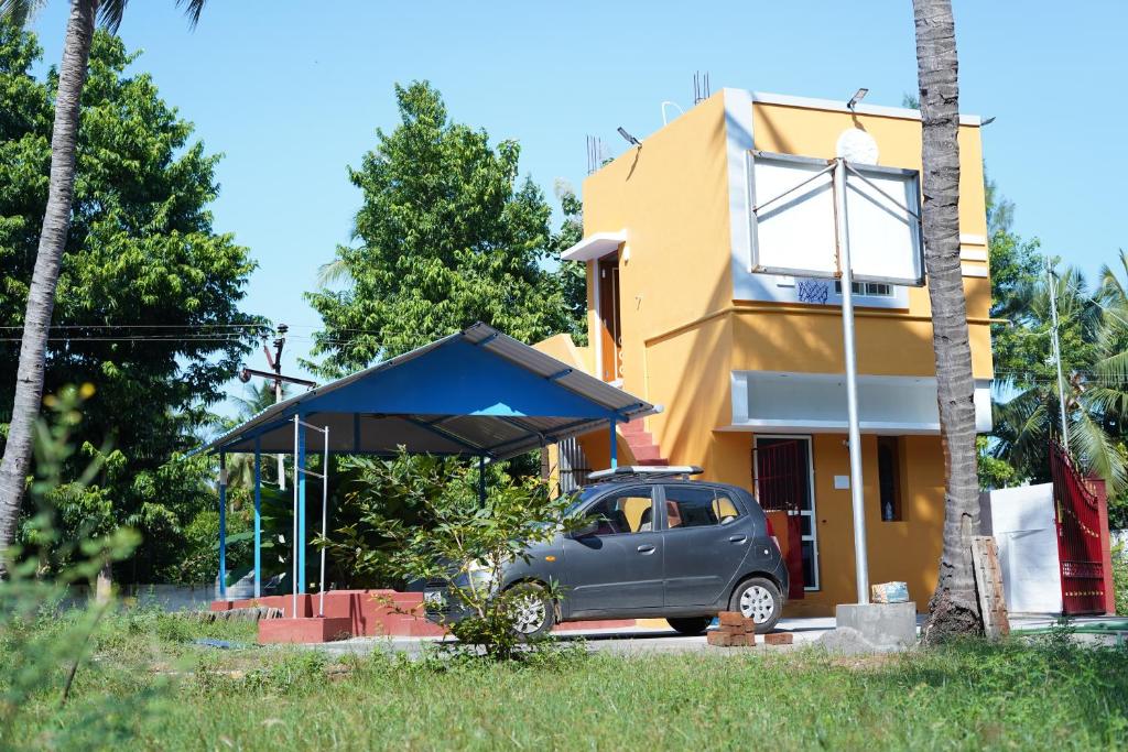 Kālapettai的住宿－Prism Holiday Resort PONDICHERRY Kalapet，停在黄色房子前面的汽车
