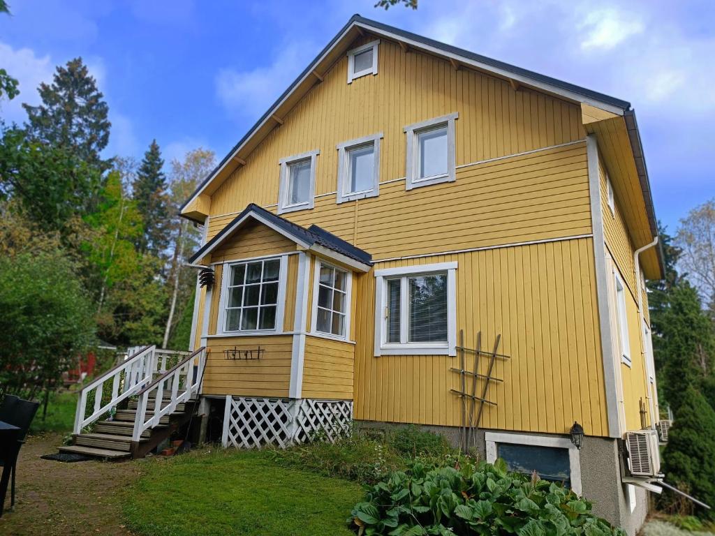 ein gelbes Haus mit weißen Fenstern und einer Treppe in der Unterkunft Perheystävällinen Paritalo Raisio in Raisio