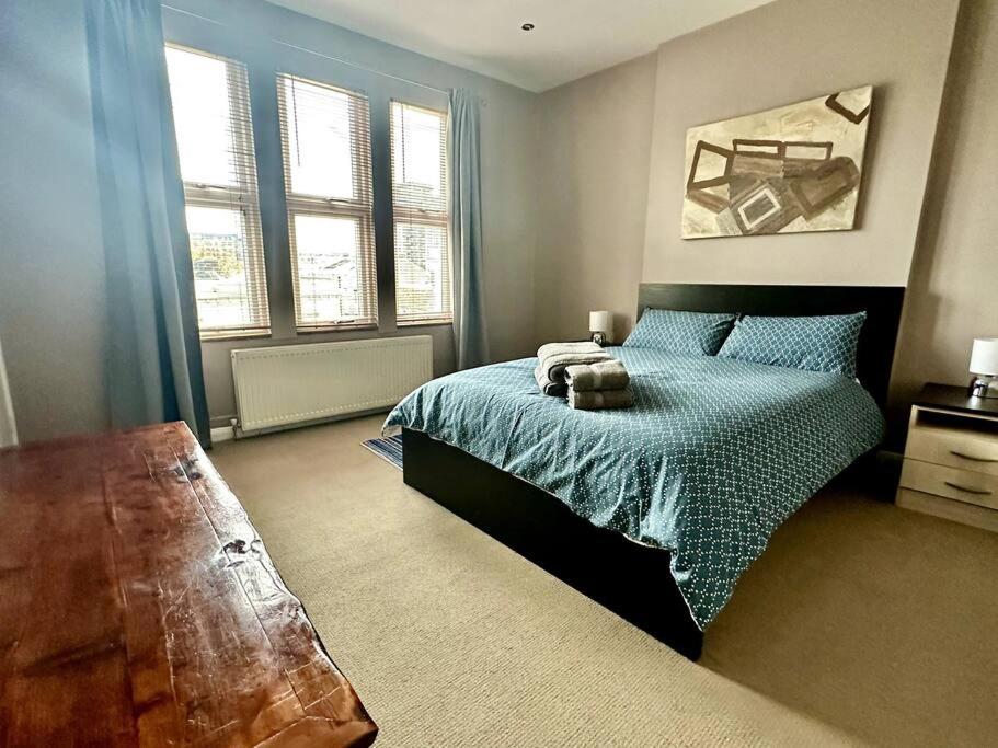 1 dormitorio con 1 cama con sábanas azules y ventanas en Luxury 2 bed flat Kings Road, Fulham en Londres