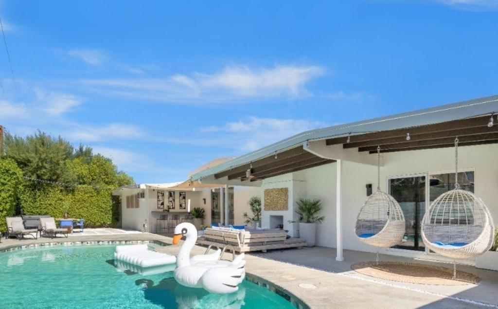 two swans in a swimming pool in front of a house at tHe PRESIDENTIAL HOUSE: EXCLUSIVE MOUNTAIN VIEWS & AMENITIES in La Quinta