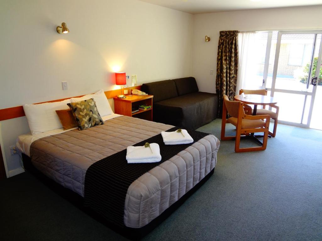 Habitación de hotel con cama y sala de estar. en Aalton Motel, en Christchurch