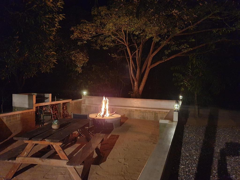 a fire pit with a picnic table and a bench at Kingfisher Creek Cottage in Hoedspruit
