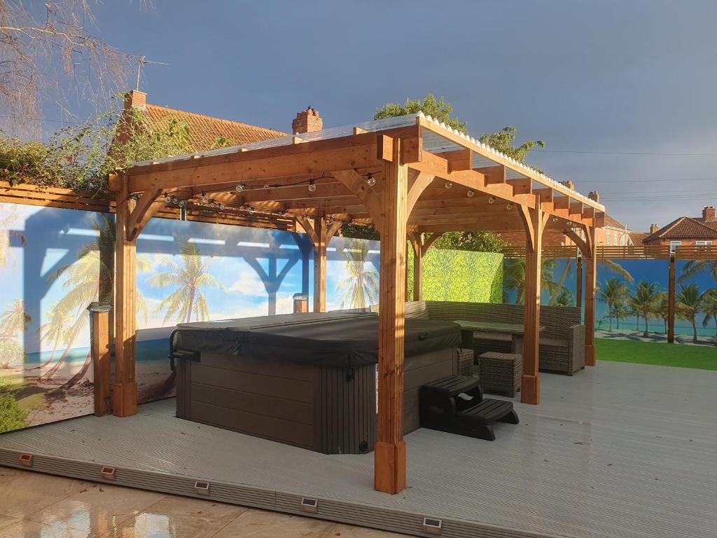 a wooden pergola on a deck with a grill at Seabar in Burnham on Sea