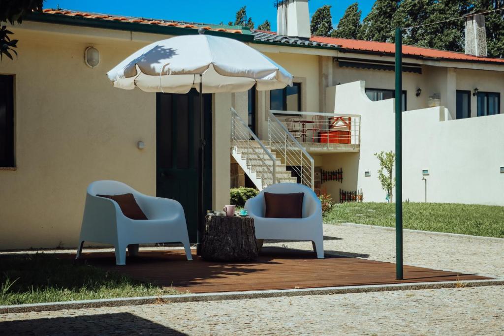 two chairs and an umbrella in front of a house at ROTA - Opo airport house in Maia