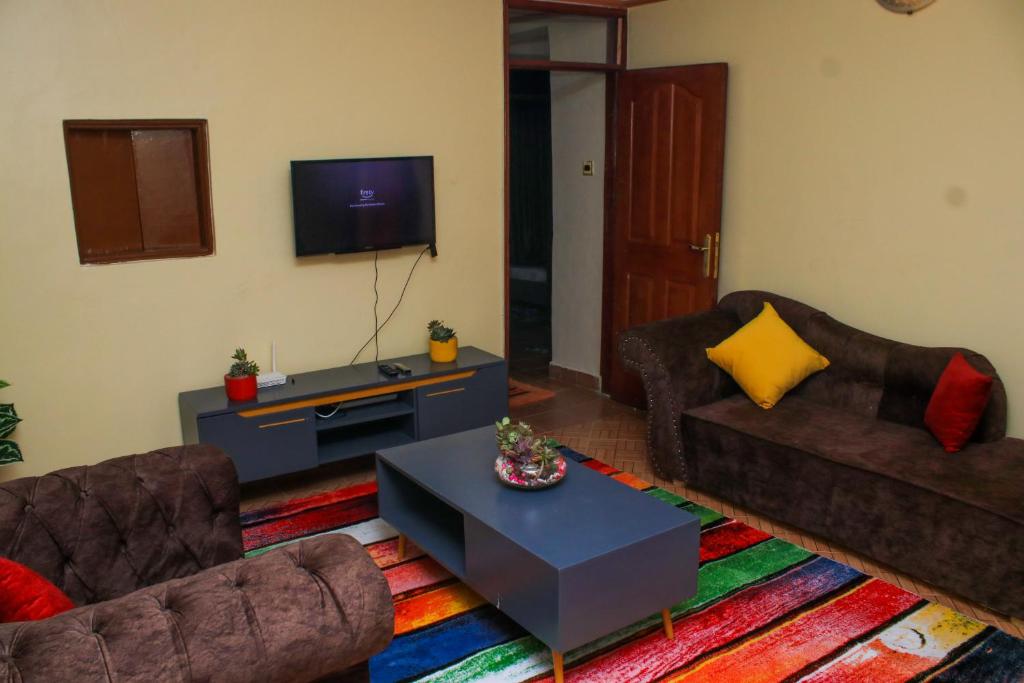 uma sala de estar com dois sofás e uma televisão em Kate's 1 bedroom furnished apartment em Kisumu