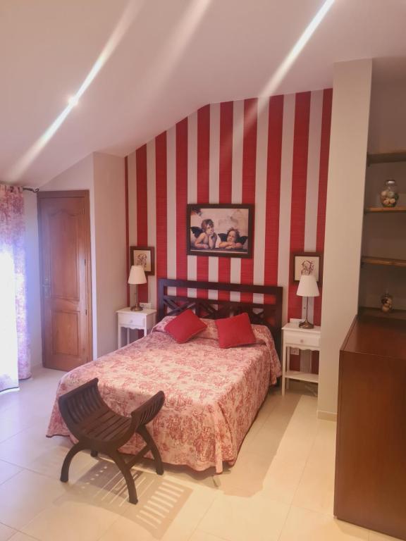 a bedroom with a bed with red and white stripes at Casa Rural La Botica in Jarandilla de la Vera