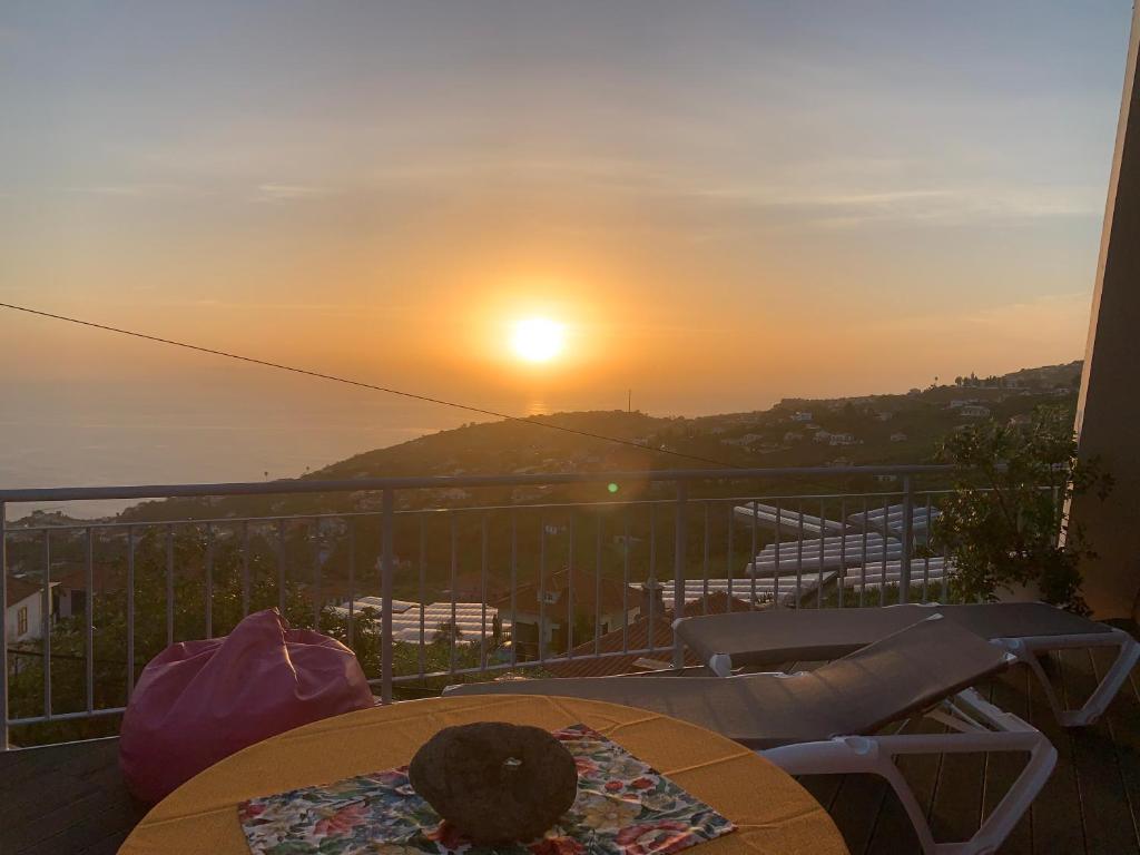 - un balcon avec une table et des chaises pour admirer le coucher du soleil dans l'établissement Studio privado com vista mar e montanha, à Ponta do Sol