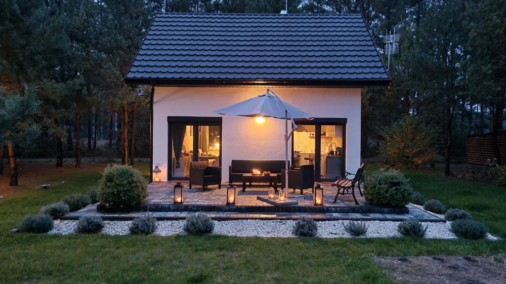 uma pequena casa com um pátio com um guarda-chuva em Domek Leśny Spokój Smyków em Celiny
