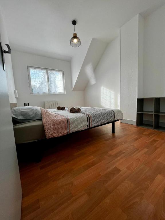 ein Schlafzimmer mit einem Bett in einem Zimmer mit Holzboden in der Unterkunft MAISON DE VILLE in La Haye-du-Puits