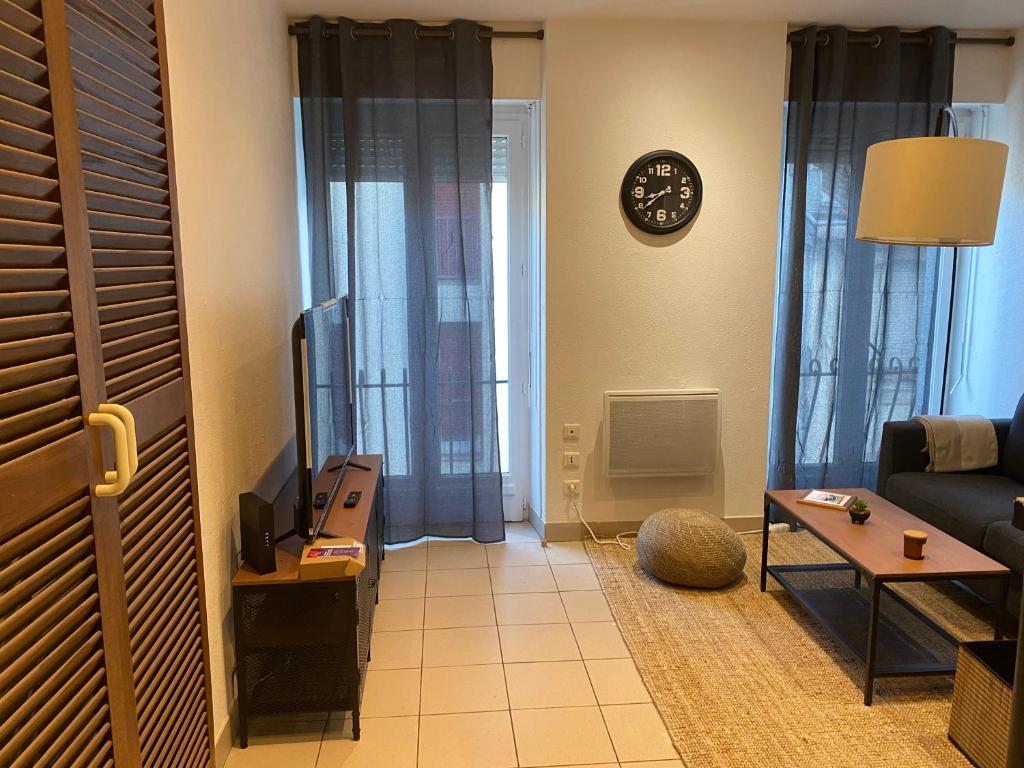 een woonkamer met een bank en een klok aan de muur bij Cozy appartement en plein coeur de Dax Fontaine Chaude in Dax
