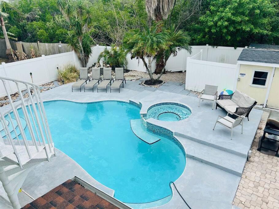 a large swimming pool with chairs and a patio at 4 Bedroom home with heated pool by the beach! in Clearwater Beach