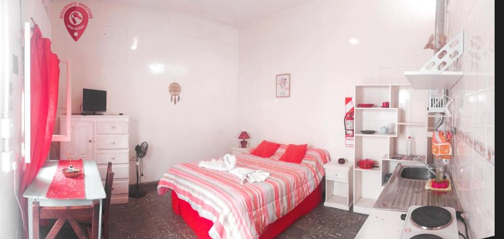 a bedroom with a bed with red pillows and a desk at Zafiro Departamentos in Capilla del Monte