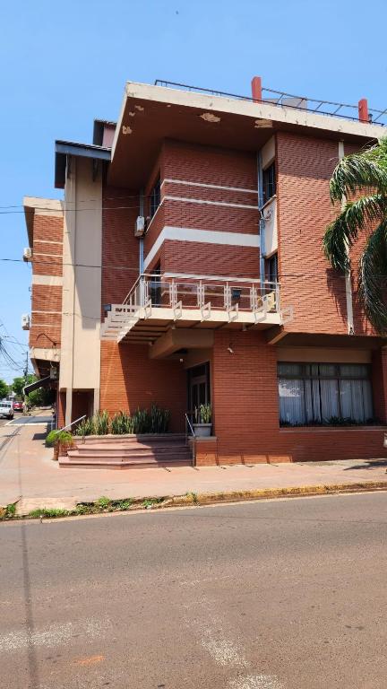ein rotes Backsteingebäude mit Balkon auf einer Straße in der Unterkunft Hotel Maria in Encarnación