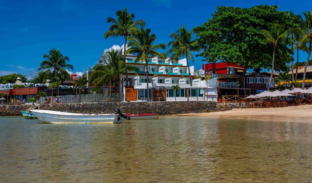 un barco sentado en el agua junto a una playa en Aqua by Sambass en Morro de São Paulo