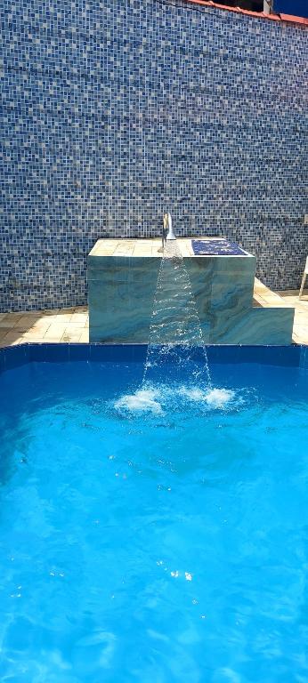 a fountain in a pool of blue water at Casa Mongagua in Mongaguá
