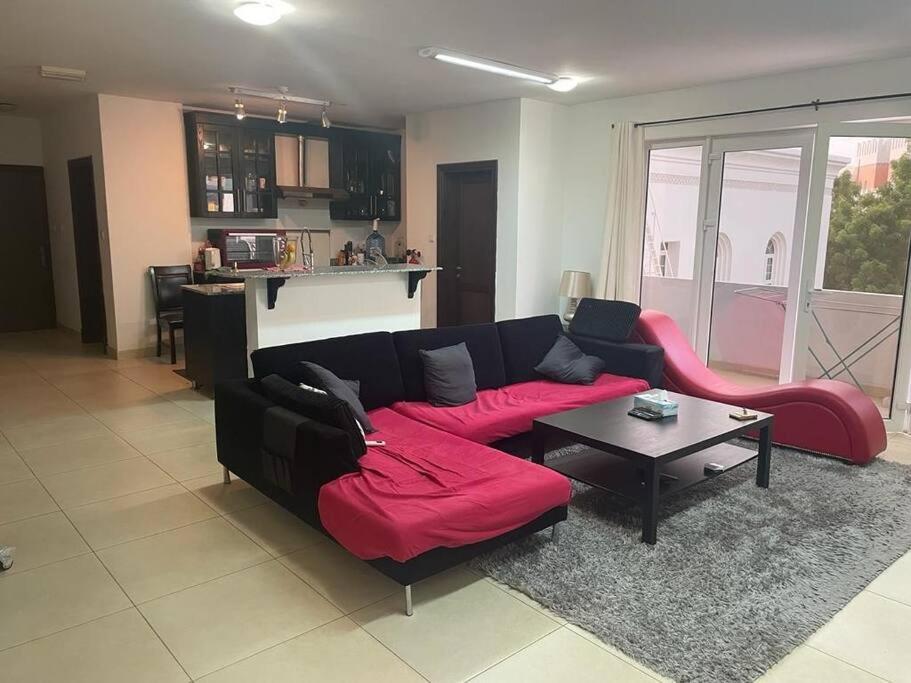 uma sala de estar com um sofá vermelho e uma mesa em Beautiful 2 Bedrooms Apartment - Azaiba em ‘Udhaybah