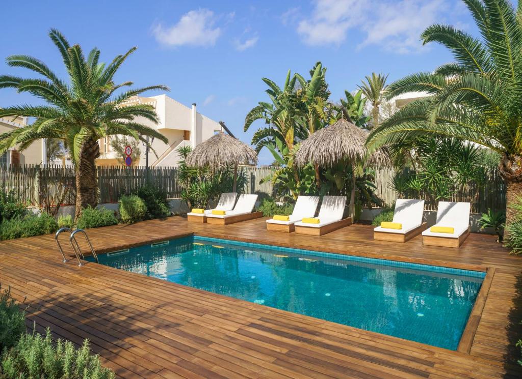 a swimming pool with lounge chairs next to a villa at Es Caló Luxe - Formentera Break in Es Calo