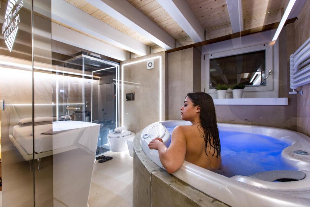 a woman sitting in a bath tub in a bathroom at Luxury Wellness Verona Spa in Verona