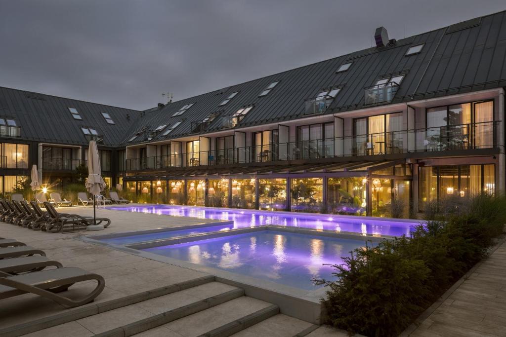 ein Hotel mit einem Pool vor einem Gebäude in der Unterkunft Hotel Saltic Resort & Spa Łeba in Łeba