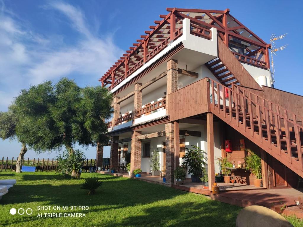 uma casa com varanda e uma árvore em Vistas al faro em Cádis