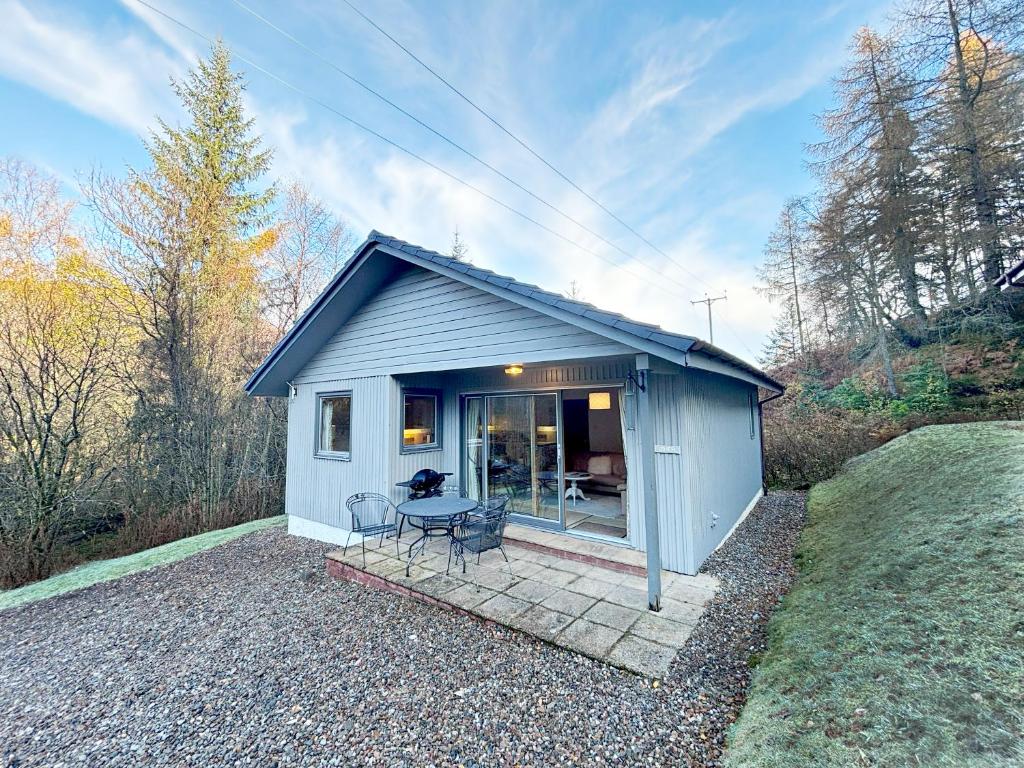a small blue shed with a table and chairs at Fisher chalet in Crianlarich