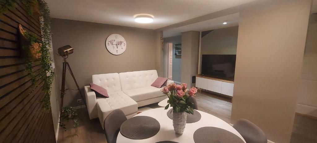 a living room with a white couch and a table with flowers at Cozy and warm just like at home, Free Parking in Langevåg