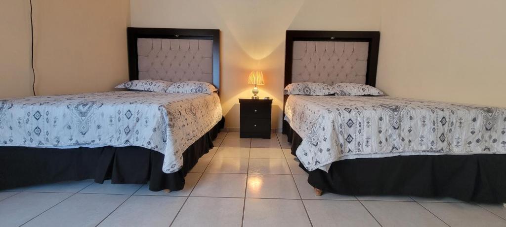 1 dormitorio con 2 camas y una lámpara en el suelo de baldosa en Alojamiento Villa Jardin, 