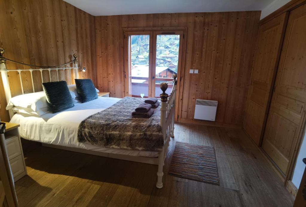 a bedroom with a bed and a large window at Slemish Apt in Morzine