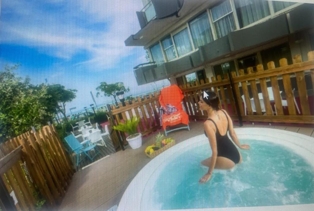 uma mulher de fato de banho sentada numa piscina em Hotel Tyc Soleti Hotels em Rimini