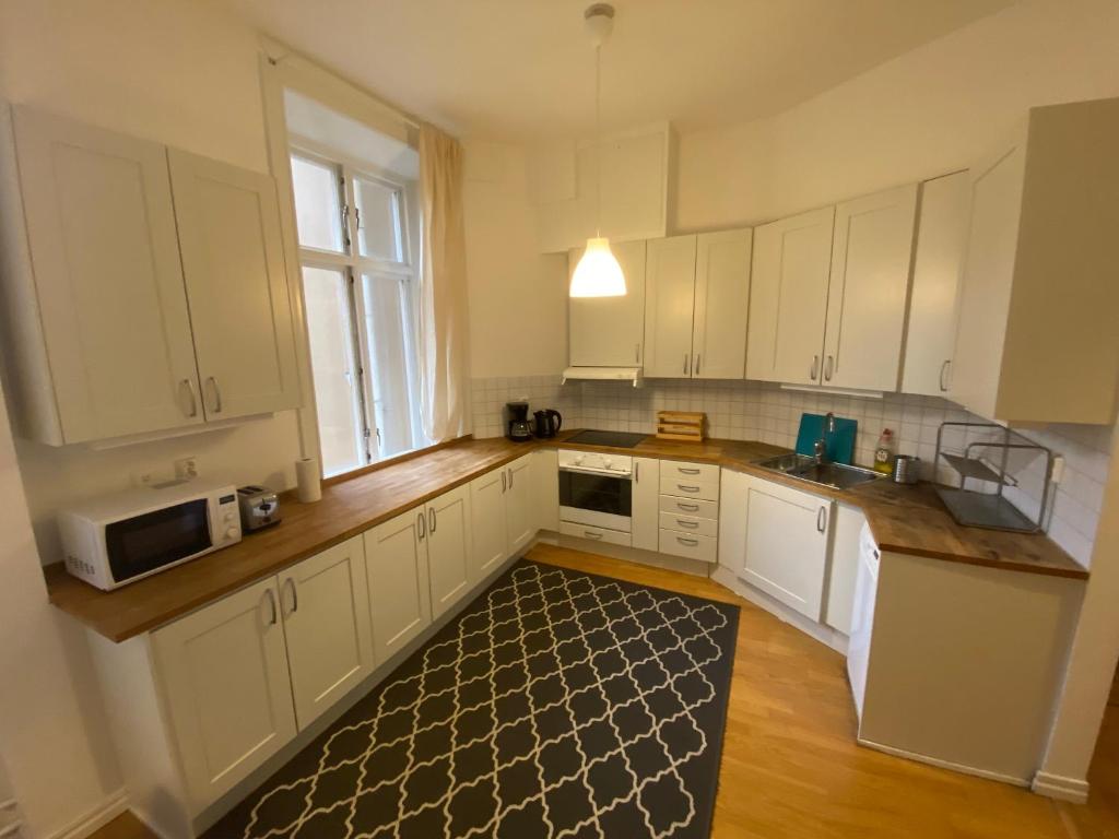 a kitchen with white cabinets and a kitchen rug at Home Inn KHT15 in Stockholm
