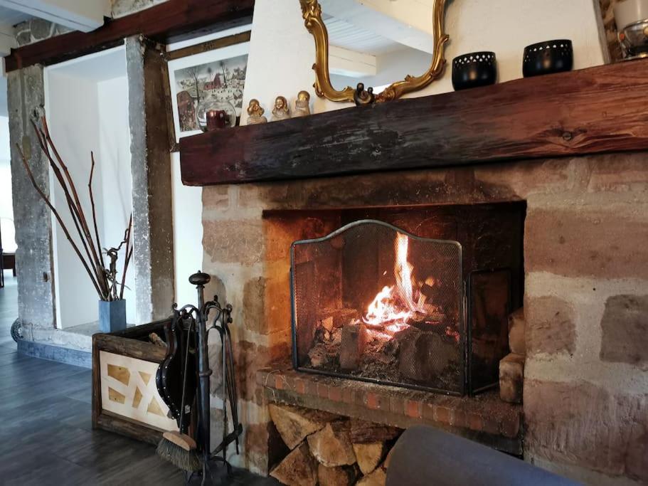 a brick fireplace with a fire in it at La Maison Thébaïde in Mortagne