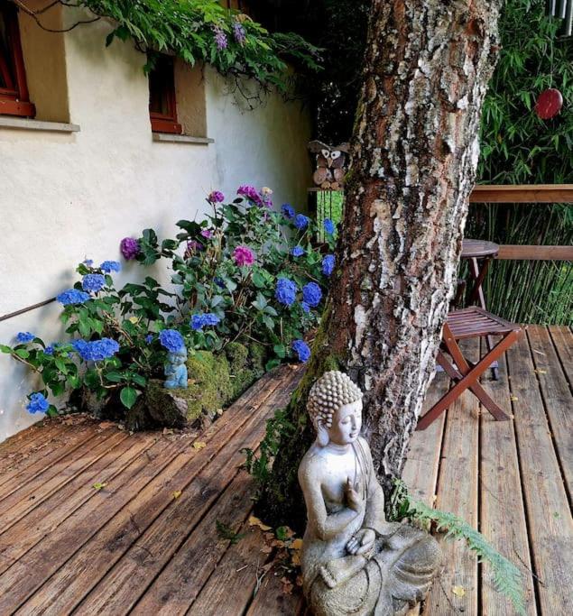 a statue sitting on a wooden deck next to a tree at La Maison Thébaïde in Mortagne