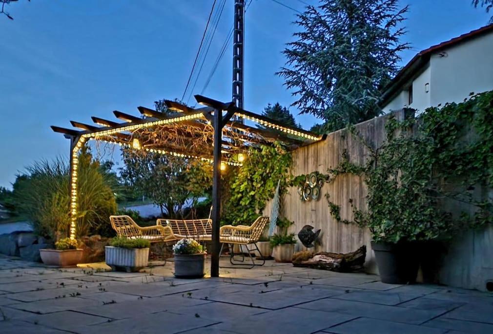 a pergola with chairs and lights on a patio at La Maison Thébaïde in Mortagne