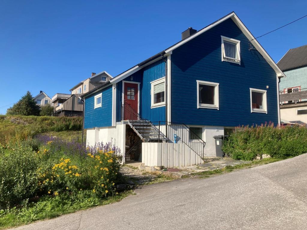 una casa azul con una puerta roja en una calle en The Blue House at the end of the World I, en Mehamn